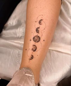 a person with a tattoo on their leg that shows phases of the moon and stars