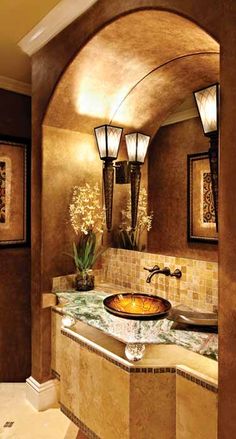 a bathroom sink sitting under two lights next to a mirror and counter top with vases on it