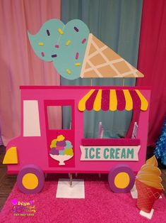 a pink ice cream truck with an ice cream cone on the top and some decorations around it