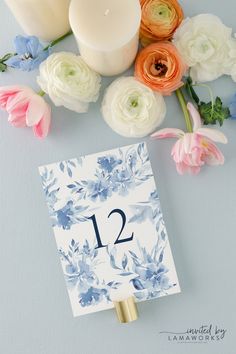 an arrangement of flowers, candles and a table number on a blue background with the number twelve