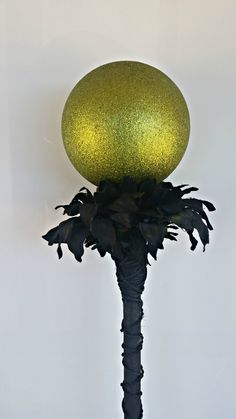 a green ball sitting on top of a palm tree in front of a white wall