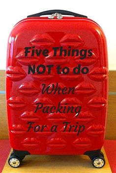 a red piece of luggage sitting on top of a wooden table