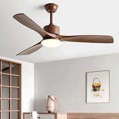 a ceiling fan in a room with white walls and wooden furniture on the floor next to a window