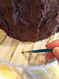 a person holding a knife near a chocolate cake