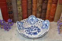 a blue and white bowl sitting on top of a table in front of some books