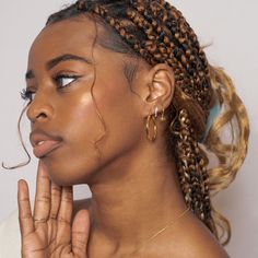 a woman with braids on her head and hand in front of her face