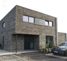 a car parked in front of a brick building with two windows on the top floor