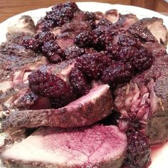 a white plate topped with meat and cranberry sauce on top of a wooden table