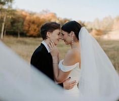 a bride and groom standing together in the grass