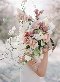 a woman holding a bouquet of flowers in her hands