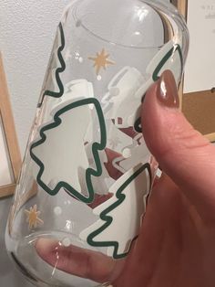 a hand holding a glass with christmas trees on it