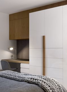 a bedroom with a bed, desk and cupboards in the corner next to it