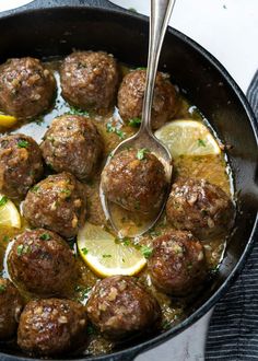 a skillet filled with meatballs and lemons