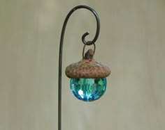 a bird is perched on top of a small glass ball hanging from a metal pole