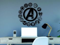 a desk with a laptop on it in front of a wall that has an avengers symbol