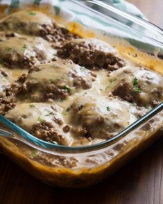 a casserole dish with meatballs and gravy in it on a wooden table