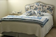 a bed with blue and white pillows on it's headboard in a bedroom