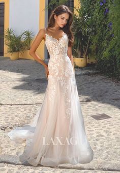 a woman in a white wedding dress standing on a cobblestone walkway with her hands on her hips