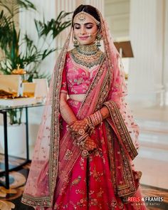 a woman in a pink and gold bridal gown is smiling at the camera while holding her hand out