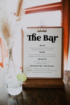 the bar menu is displayed in front of a glass vase with a feather on it