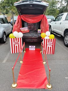 the back end of a car that is decorated with red and white striped curtains, popcorn boxes, and balloons