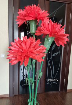 three red flowers are in a green vase