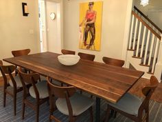 a dining room table with chairs and a bowl on it in front of a staircase