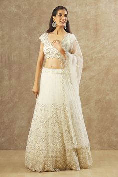 Off-white net lehenga with an attached cancan and pearl hand embroidery. Comes with a padded blouse and a dupatta. Components: 3 Pattern: Hand embroidered Type Of Work: Pearl Neckline: Round Sleeve Type: Scalloped Sleeves Fabric: Net Color: Off White Other Details:  Attached lining Lehenga length : 45 inches Approx Product Weight : 5-10 Kgs Closure : Lehenga : Side zip Blouse : Back hooks and Drawstrings Occasion: Bride,Wedding - Aza Fashions Festive Off White Choli With Sheer Dupatta, Bollywood Style Net Sets For Wedding, Bollywood Style Wedding Net Sets, Bollywood Style Wedding Sets In Net, Bollywood Net Wedding Sets, Reception Lehenga In Off White With Sheer Dupatta, Off White Lehenga With Sheer Dupatta For Reception, Festive Off-white Choli With Sheer Dupatta, White Anarkali Pre-draped Saree With Dupatta