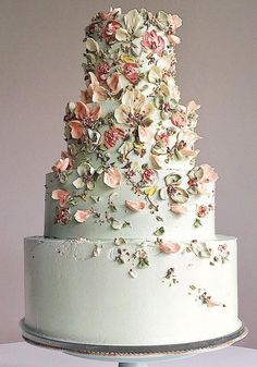 a three tiered white cake with pink flowers on top