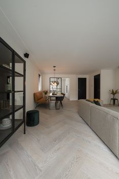 a living room filled with furniture next to a dining table and bookshelf on top of a hard wood floor