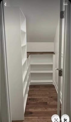 an empty walk in closet with white shelving and wood flooring on the walls