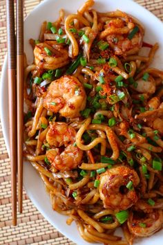 a white plate topped with shrimp and noodles next to chopsticks