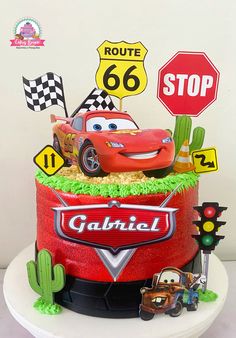 a birthday cake with cars on top and street signs in the background, including a stop sign