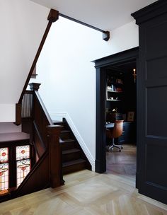 the stairs lead up to an office area with stained glass windows and wooden railings