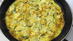 an omelet with zucchini and cheese in a pan on the stove