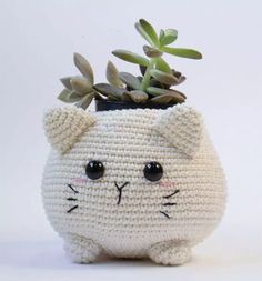 a crocheted cat planter with succulents in it's mouth