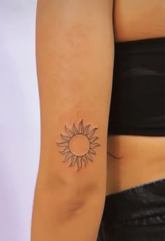 a woman's arm with a small sun tattoo on the left side of her right arm