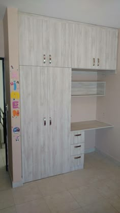 an empty room with white cupboards and drawers on the wall next to a tiled floor