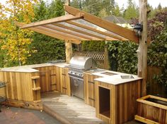 an outdoor kitchen is built into the side of a wooden structure with grill and sink