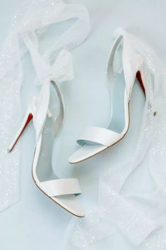 a pair of white high heeled shoes sitting on top of a table