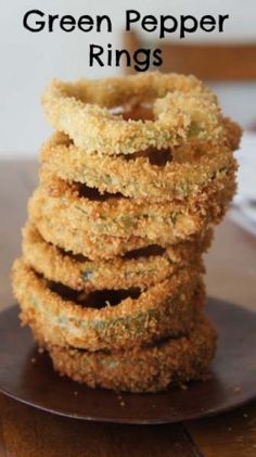 a stack of fried green pepper rings sitting on top of a wooden plate with text overlay