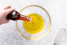 someone is pouring olive oil into a glass bowl