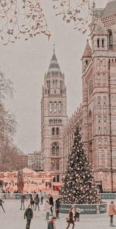 people skating on an ice rink with a christmas tree in the foreground and large buildings in the background