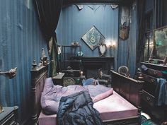 an old fashioned bedroom with blue walls and purple bedding, including a pink mattress