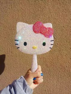 a person holding up a hello kitty fan with sequins on it's face