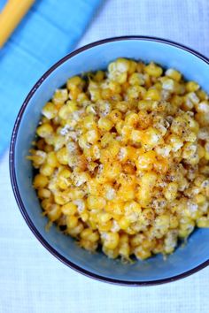 a blue bowl filled with corn on top of a table