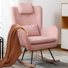 a pink rocking chair in a living room with a blanket on the armrests