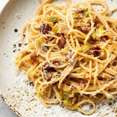 a white plate topped with pasta and bacon