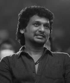 a black and white photo of a man with curly hair looking up at the camera