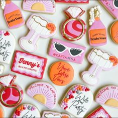 many decorated cookies are arranged on a table with pink and orange accents, such as name tags